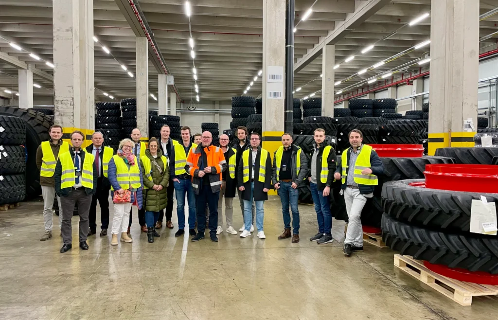 Ausflug der Wirtschaftjunioren, sie tragen jeweils eine gelbe Warnweste und sind in einer Halle voller Reifen