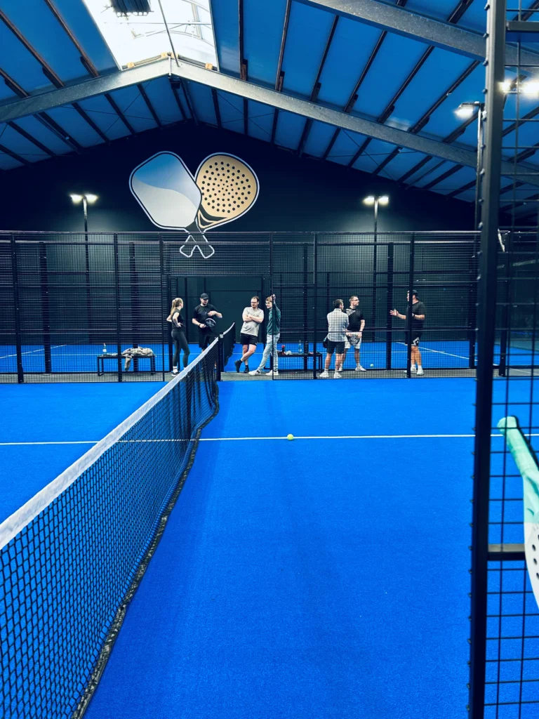Eine blaue Sporthalle, in welcher einige Personen Paddle spielen