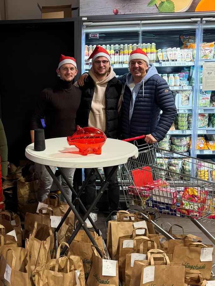 Drei Wirtschaftjunioren mit Weihnachtsmütze und gepackten Lebensmitteltüten für einen wohltätigen Zweck